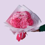 A bouquet of pink hydrangeas wrapped in white paper with a pink ribbon.