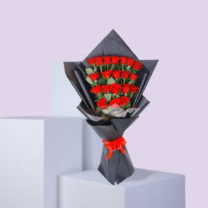 A bouquet of red roses wrapped in black paper with a red ribbon.