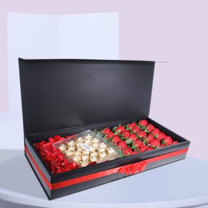 A black gift box open to reveal a compartment of red roses and another compartment of Ferrero Rocher chocolates.