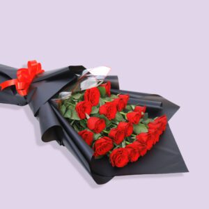 A bouquet of red roses wrapped in black paper with a red ribbon.