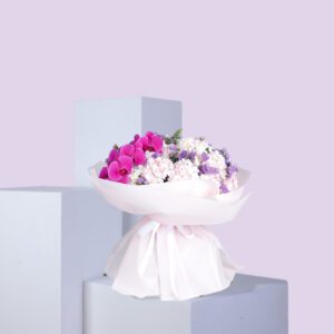 A bouquet of pink orchids and white hydrangeas wrapped in white paper with a pink ribbon.