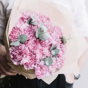 a bouquet of pink carnations wrapped in light brown paper