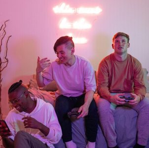 the left is seated on the floor, leaning against the bed, and is engrossed in a handheld device, possibly a phone or another gaming console